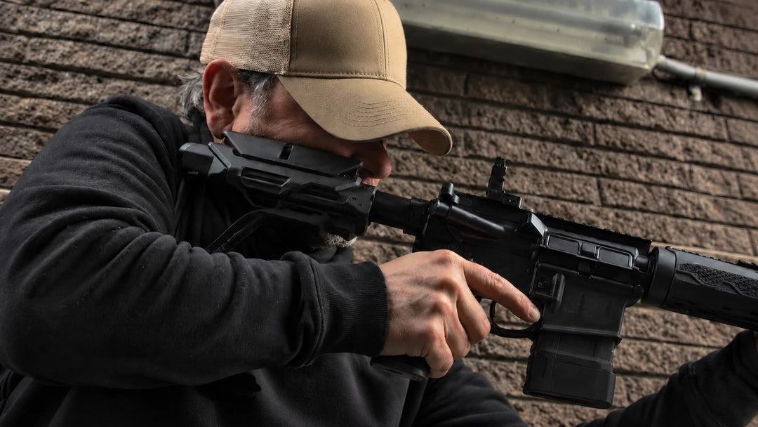 Shooter in a tan trucker cap and black hoodie against a brick wall