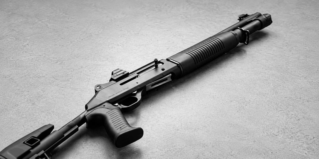 Black tactical shotgun lying on a concrete floor